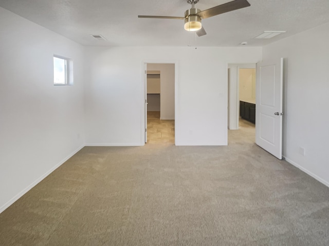 spare room featuring baseboards, visible vents, a ceiling fan, and light colored carpet