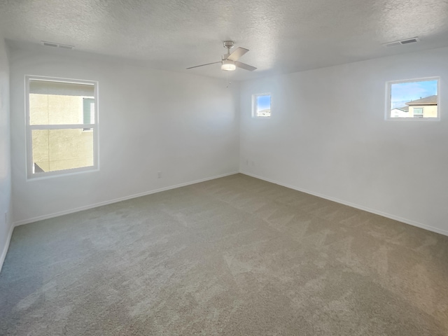 carpeted spare room with a textured ceiling, ceiling fan, visible vents, and baseboards