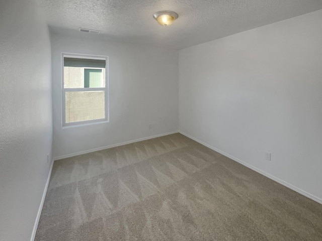 unfurnished room featuring a textured ceiling, carpet floors, visible vents, and baseboards