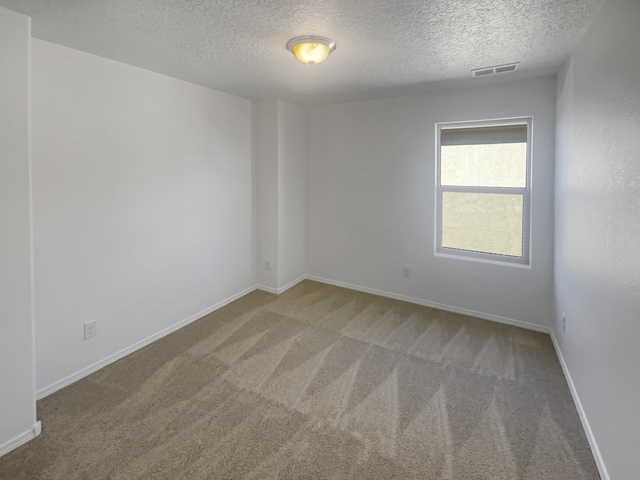 carpeted empty room featuring a textured ceiling, visible vents, and baseboards