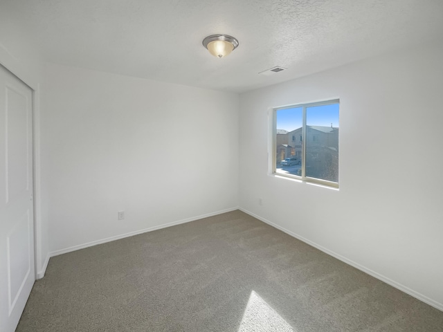 carpeted empty room with a textured ceiling, visible vents, and baseboards