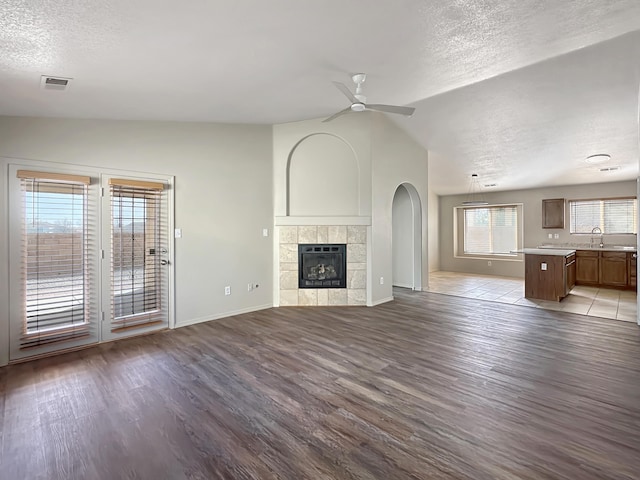 unfurnished living room with lofted ceiling, visible vents, a ceiling fan, a sink, and wood finished floors