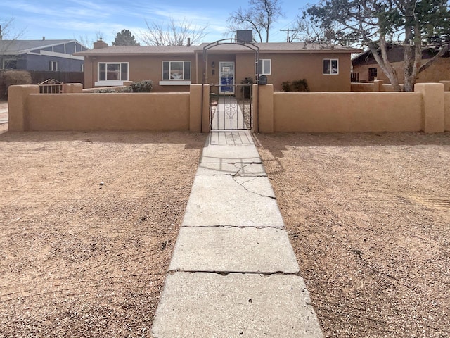 view of front of property with a fenced front yard, a gate, and stucco siding