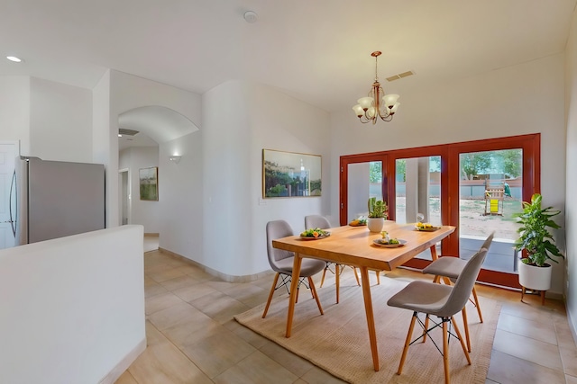 dining room with light tile patterned floors, baseboards, visible vents, arched walkways, and a notable chandelier