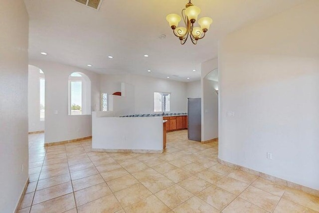 kitchen with visible vents, brown cabinetry, open floor plan, freestanding refrigerator, and a chandelier