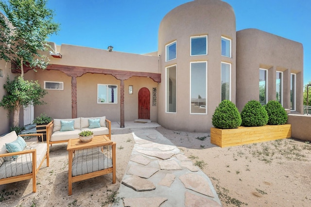 pueblo-style house with a patio area, an outdoor living space, and stucco siding