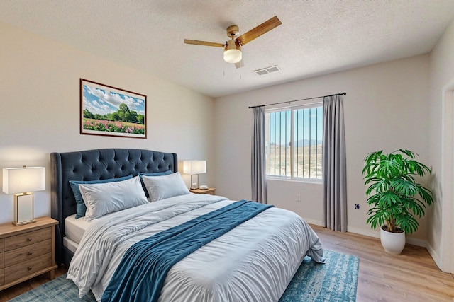 bedroom with visible vents, ceiling fan, a textured ceiling, light wood-type flooring, and baseboards