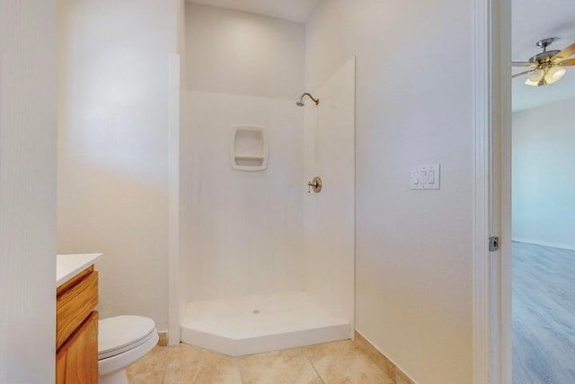 bathroom featuring ceiling fan, tile patterned flooring, toilet, vanity, and walk in shower