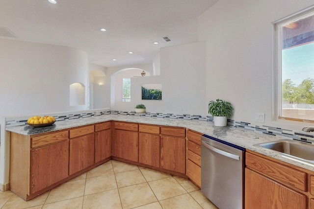 kitchen with light tile patterned floors, stainless steel dishwasher, a sink, and decorative backsplash