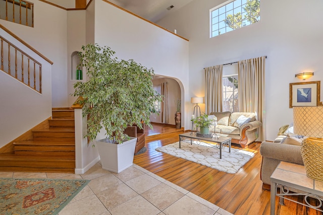 living area with stairs, arched walkways, a healthy amount of sunlight, and wood finished floors