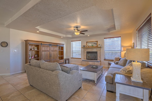 living room with a tray ceiling, a healthy amount of sunlight, and ceiling fan