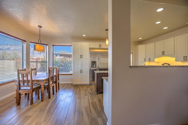 dining area featuring a textured ceiling, light wood-type flooring, baseboards, and recessed lighting