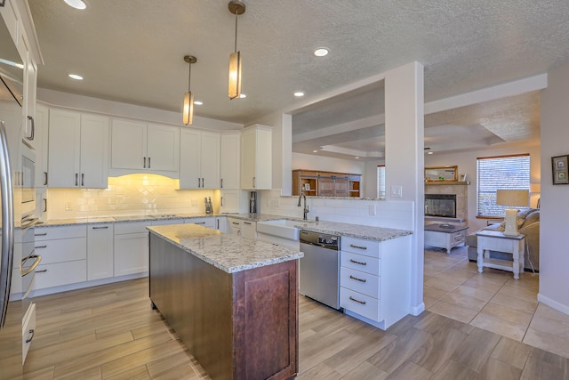 kitchen with a center island, tasteful backsplash, stainless steel dishwasher, white cabinetry, and a sink