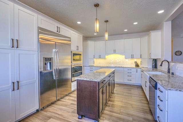 kitchen with white cabinetry, a sink, and built in appliances