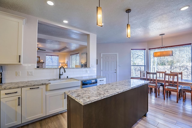 kitchen with tasteful backsplash, light wood-type flooring, a sink, and white cabinetry