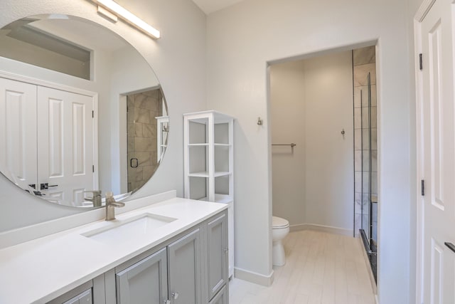 full bath with toilet, a shower stall, baseboards, and vanity