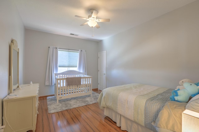 bedroom featuring a ceiling fan, baseboards, visible vents, and wood finished floors