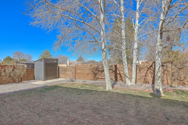 view of yard with a storage shed, a fenced backyard, and an outdoor structure