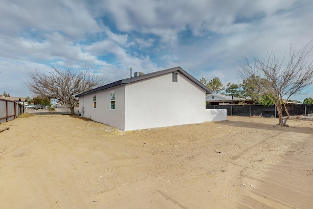 view of side of property featuring fence and stucco siding