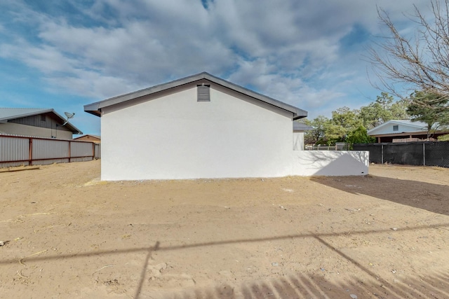 view of side of property featuring stucco siding and fence