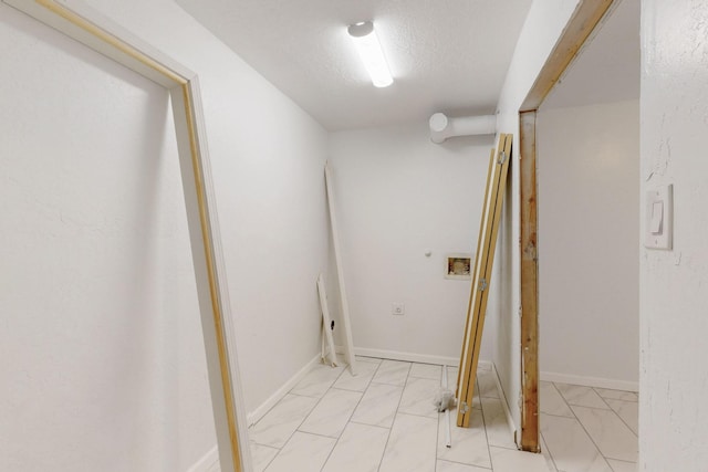 corridor with marble finish floor, a textured ceiling, and baseboards