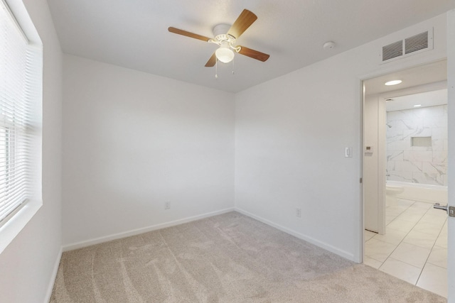 spare room with light carpet, visible vents, baseboards, and ceiling fan