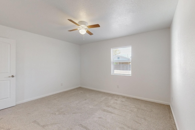 spare room with light carpet, a textured ceiling, baseboards, and a ceiling fan