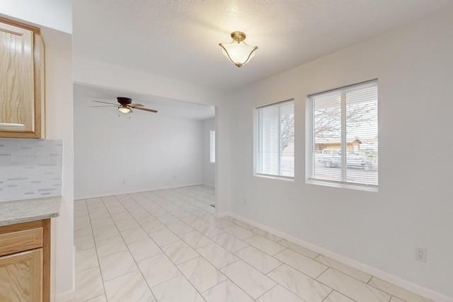 unfurnished living room with baseboards and ceiling fan