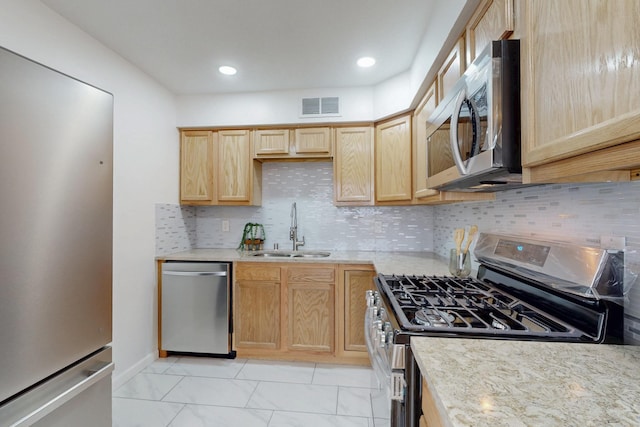 kitchen featuring visible vents, light brown cabinetry, decorative backsplash, appliances with stainless steel finishes, and a sink