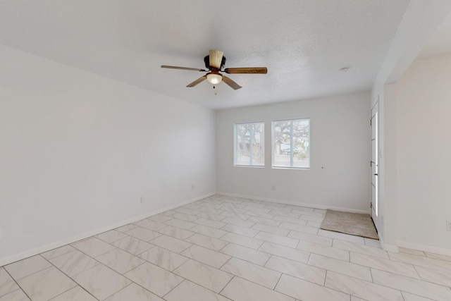 empty room with a ceiling fan and baseboards