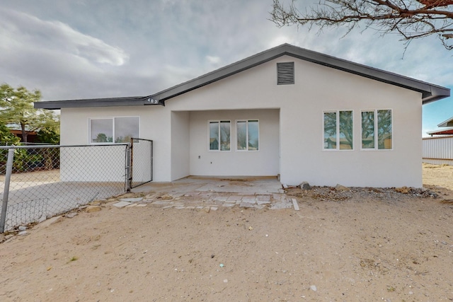 back of property with stucco siding and fence