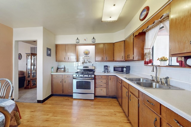 kitchen featuring appliances with stainless steel finishes, light wood-type flooring, light countertops, and a sink