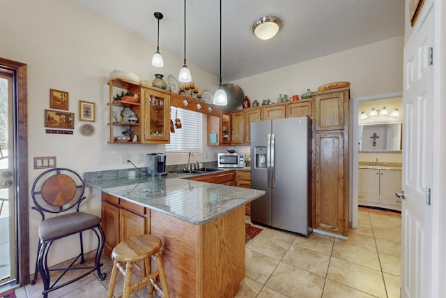 kitchen featuring brown cabinetry, a breakfast bar area, appliances with stainless steel finishes, a peninsula, and a sink