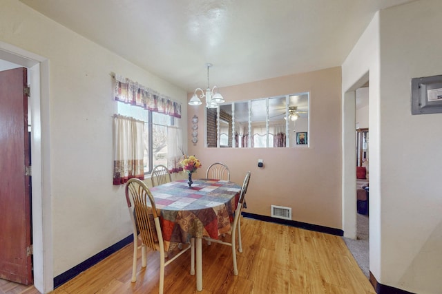 dining area with light wood-style floors, baseboards, visible vents, and an inviting chandelier