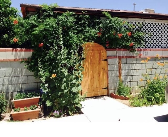 view of outdoor structure with a gate, a garden, and fence