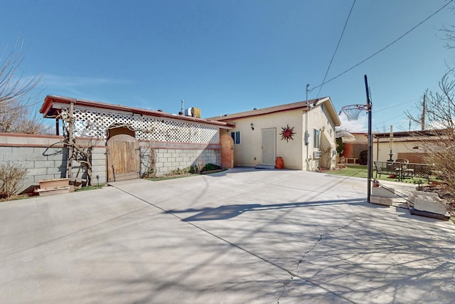 back of house with a gate, fence, a patio, and stucco siding