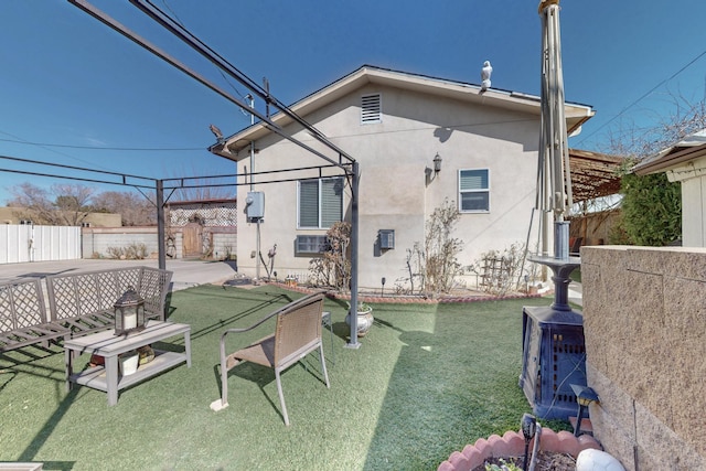 back of house featuring a patio area, fence, a lawn, and stucco siding