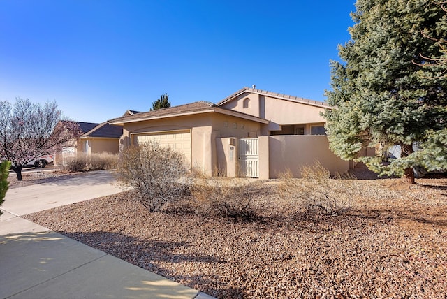 view of front of house with stucco siding, concrete driveway, an attached garage, and fence