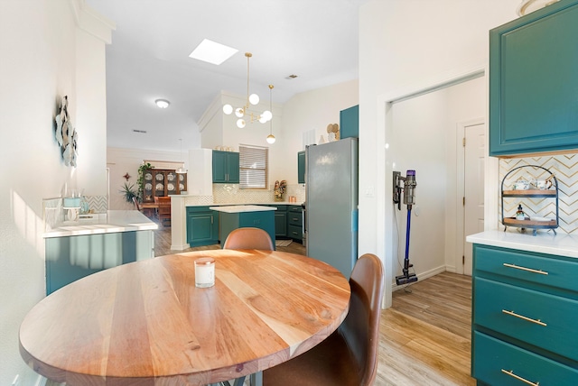 dining space with vaulted ceiling with skylight, a chandelier, and light wood finished floors