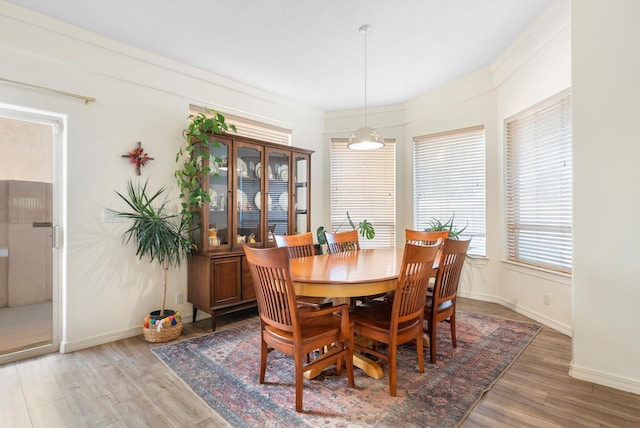 dining area with baseboards, light wood finished floors, and ornamental molding