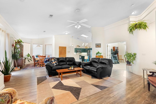 living area with visible vents, light wood-style flooring, crown molding, and vaulted ceiling