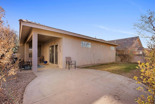 rear view of property featuring a patio area, stucco siding, and a lawn