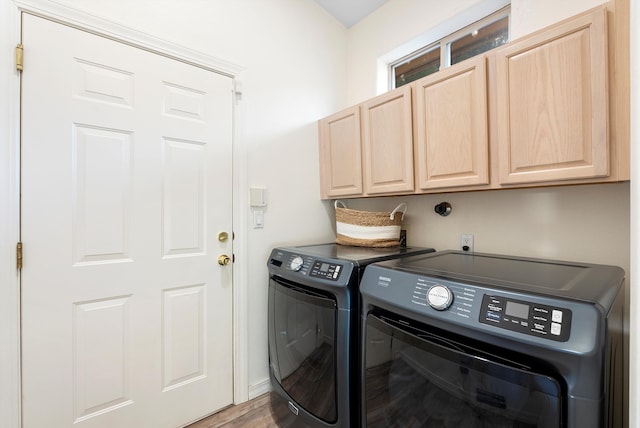 laundry area featuring washing machine and dryer, cabinet space, and wood finished floors