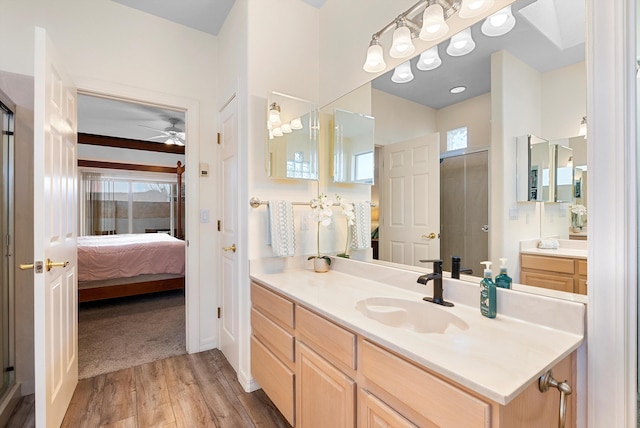 full bathroom featuring wood finished floors, connected bathroom, a shower stall, ceiling fan, and vanity