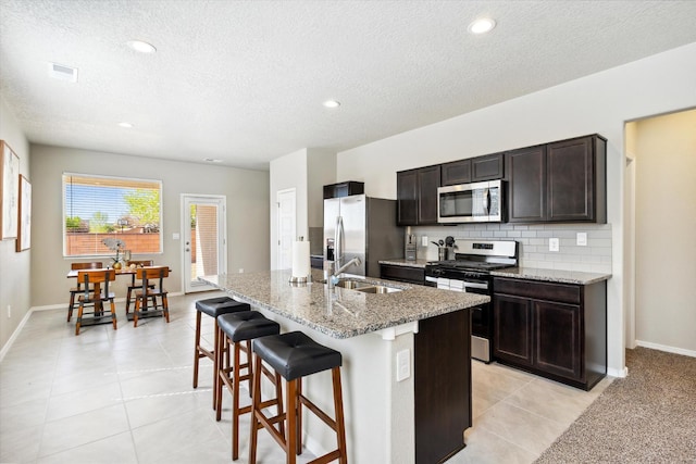 kitchen featuring visible vents, appliances with stainless steel finishes, backsplash, a breakfast bar area, and a sink