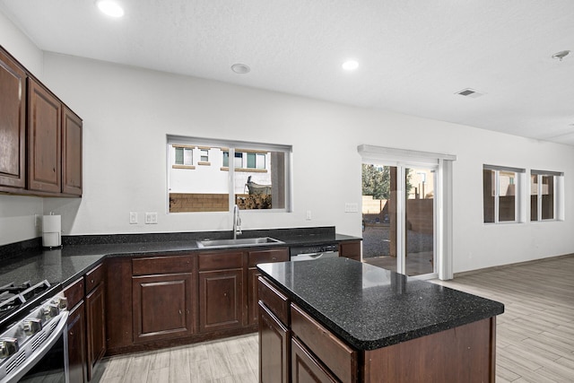 kitchen with a kitchen island, a sink, visible vents, stainless steel gas range, and light wood-type flooring