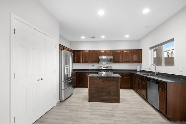 kitchen with visible vents, dark countertops, a center island, stainless steel appliances, and a sink