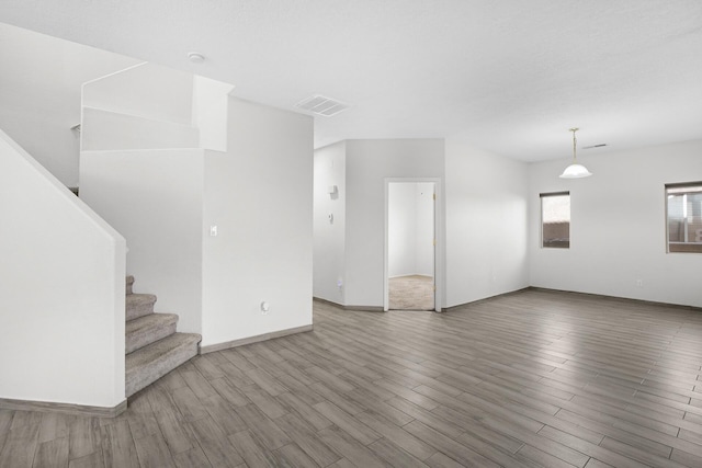 unfurnished living room featuring baseboards, stairs, visible vents, and wood finished floors