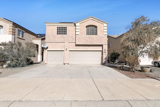 view of front of home featuring a garage, concrete driveway, roof mounted solar panels, and stucco siding