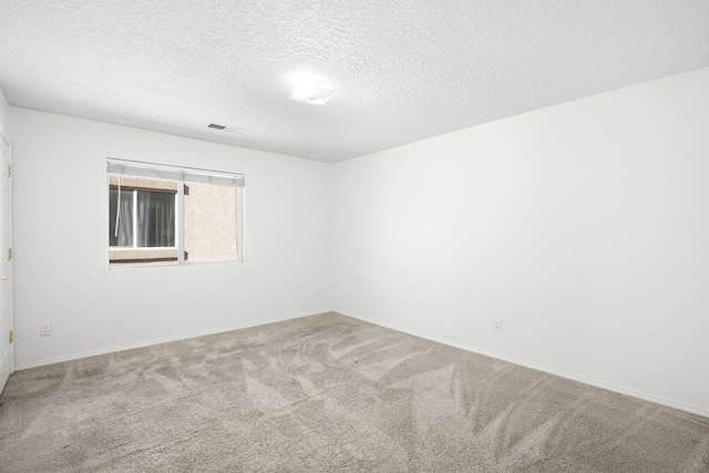 carpeted spare room featuring baseboards, visible vents, and a textured ceiling